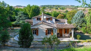A two-story house with a tiled roof, a stone foundation, and a small patio with outdoor seating. - Cozy home in Catignano with house a mountain view (Catignano)