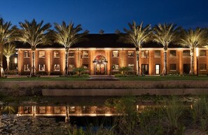 Stunning hotel entrance with a central archway, surrounded by palm trees and a serene water feature.