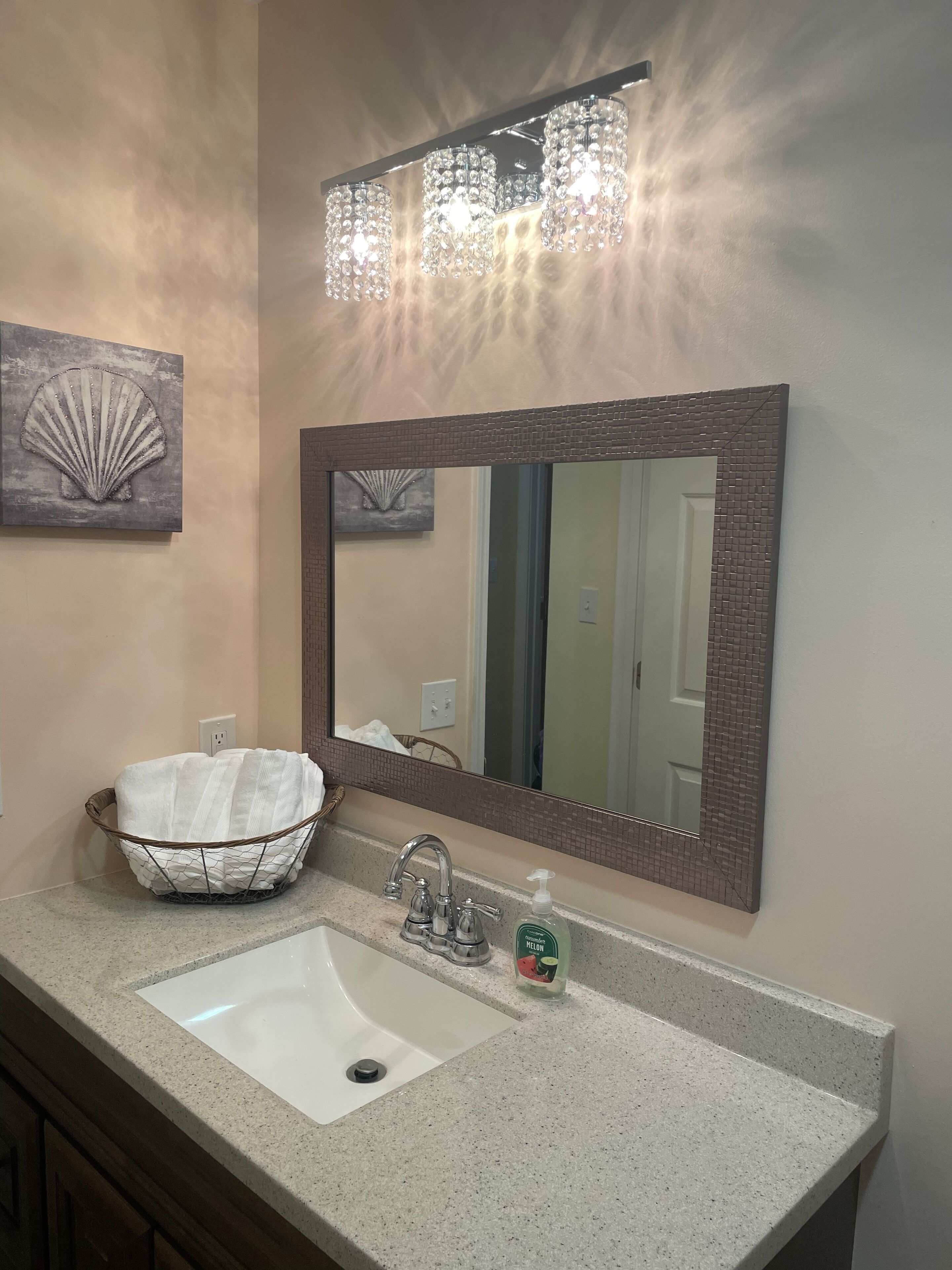 A bathroom with a large mirror, a sink, and a decorative basket.