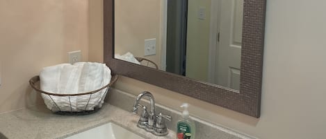 A bathroom with a large mirror, a sink, and a decorative basket.
