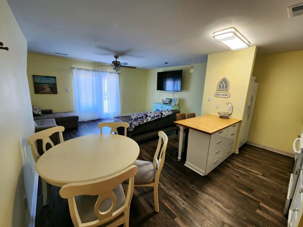 A compact living space with a dining area, a sofa, a television, and a kitchenette.