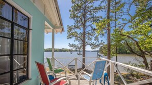 Une terrasse en bois avec des chaises colorées donnant sur un lac.