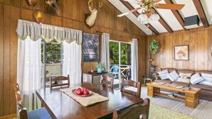 Un intérieur en bois comprenant une table à manger, des chaises, un canapé et un ventilateur de plafond.