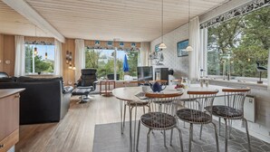 A modern kitchen with a dining area, wooden ceiling, and large windows offering a view of the outdoors. - 3 bedroom stunning home in Ringkøbing (Ringkøbing)
