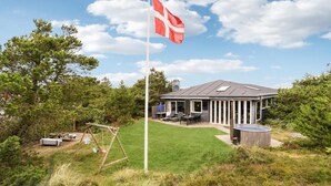 A house with a flag, a patio, and a swing set. - 3 bedroom stunning home in Ringkøbing (Ringkøbing)