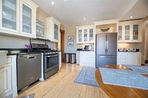 Enjoy cooking in this well-equipped kitchen with stainless steel appliances, a wooden dining table, and glass-front cabinetry.