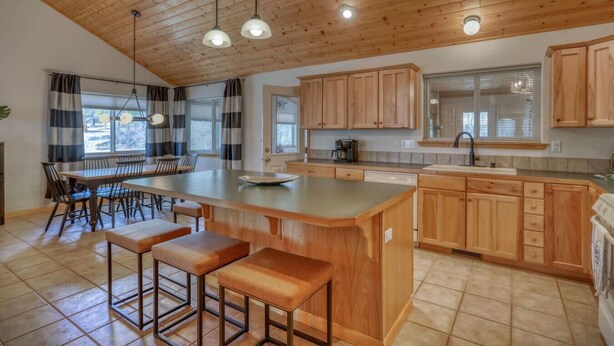 Una cocina amplia con armarios de madera, una isla grande con taburetes e iluminación colgante.