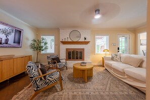A living room with a fireplace, a sofa, a coffee table, and a TV.