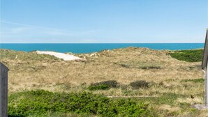Eine Küstenlandschaft mit Dünen, einer Sandfläche und Blick auf das Meer.