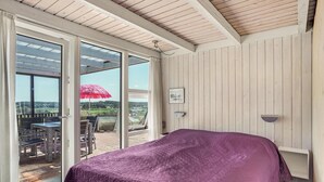 Ein Schlafzimmer mit einem großen Bett, Blick ins Freie und einer Holzbalkendecke.