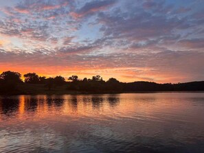 A calm lake at sunset with a silhouette of trees and hills in the background. - Belle Cottage - on the shores of Table Rock Lake, walk to the water to swim, padde, relax (Eagle Rock)
