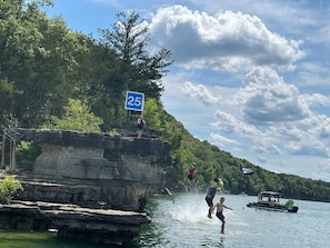 Une falaise rocheuse avec un panneau indiquant une limite de vitesse de 40 km/h, une étendue d'eau et un bateau en arrière-plan.