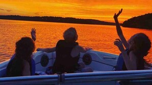 Una barca con tre persone che ammirano il tramonto.