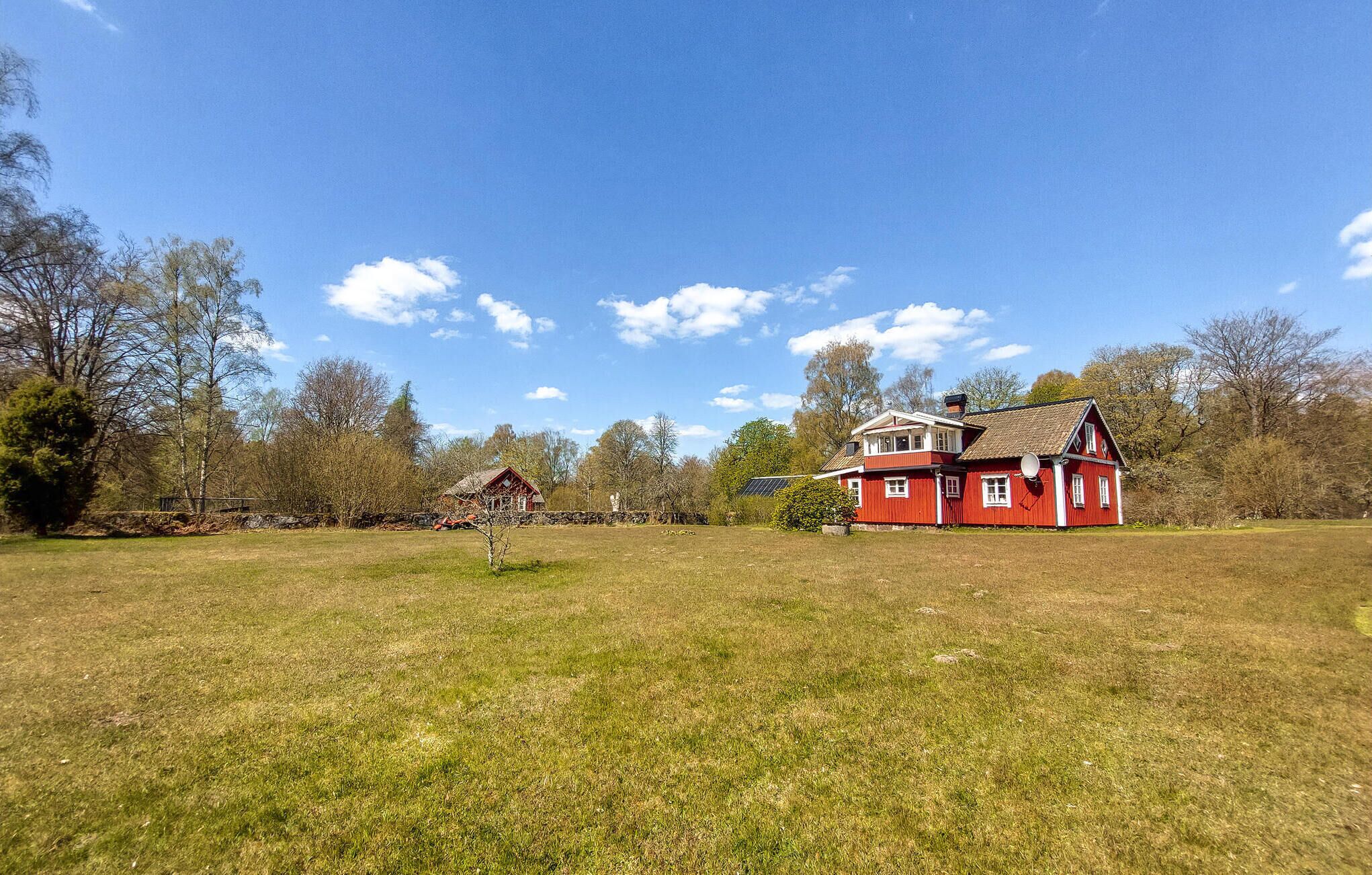A red house with a large yard and a smaller structure nearby.