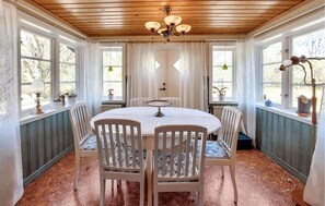 Un coin repas avec une table ronde, des chaises blanches et un lustre.