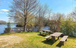 Un espace de pique-nique au bord du lac, avec des bancs et des tables en bois, entouré d’arbres et offrant une vue sur le lac.