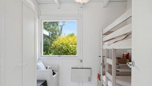 A small, white room with bunk beds, a window, and a door.