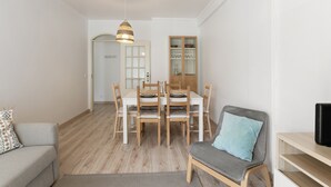 Una sala de estar moderna con una mesa de comedor, sillas, un sofá, un televisor y un mueble aparador.
