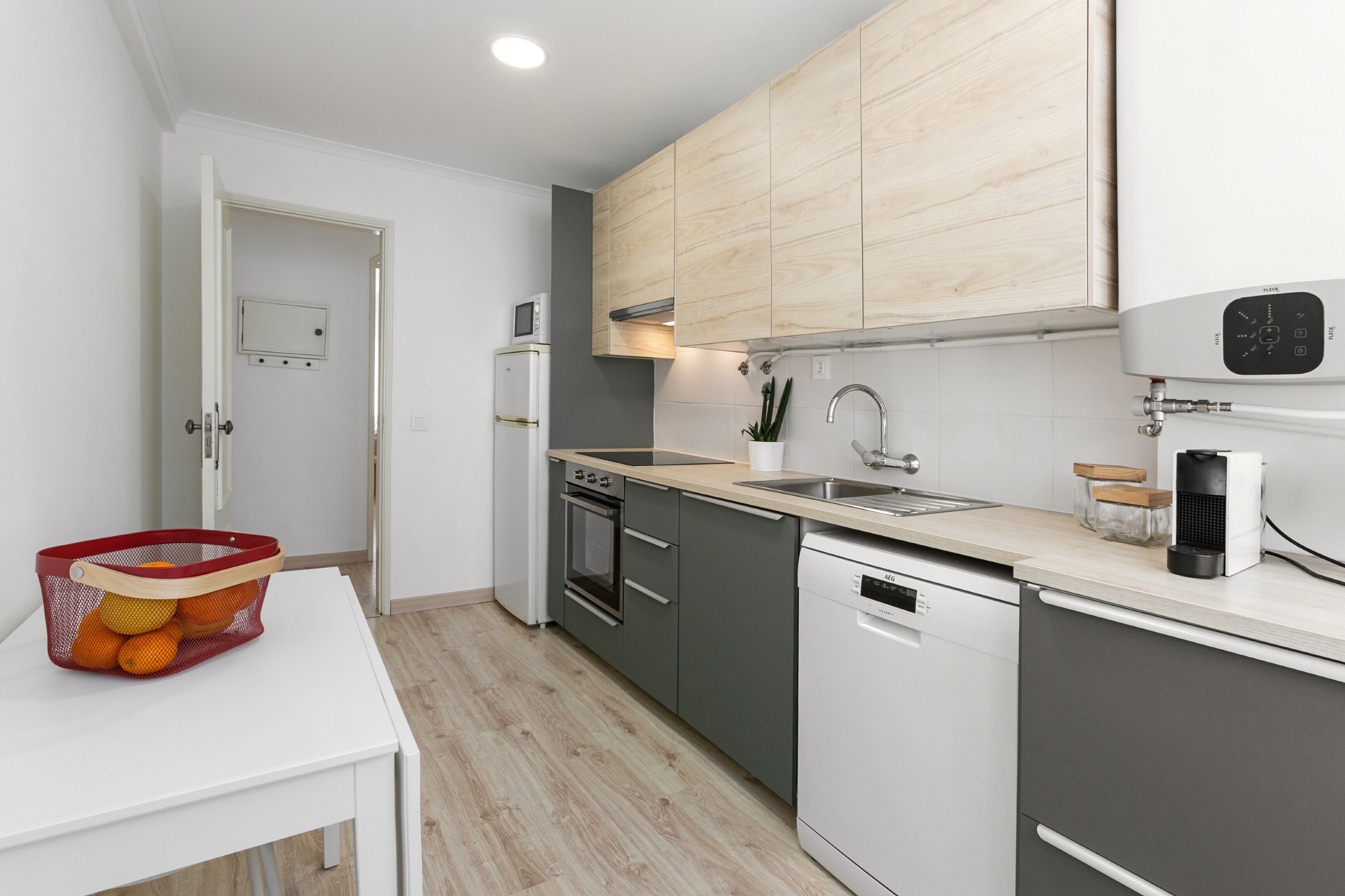 A modern kitchen with grey cabinets, a white dishwasher, a microwave, and a sink.