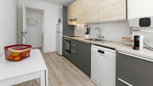 Una cocina moderna con armarios grises, un lavavajillas blanco, un microondas y un fregadero.