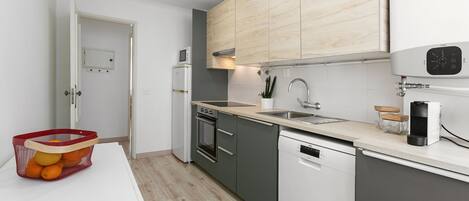 A modern kitchen with grey cabinets, a white dishwasher, a microwave, and a sink.