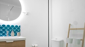 Un baño moderno con tocador de madera, inodoro y cabina de ducha de vidrio.