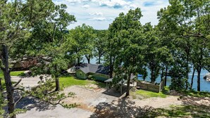 A lakeside property with a green house, a dock, and a clear view of the water.