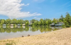 Escape to a serene lakeside retreat surrounded by lush trees and a tranquil beach.