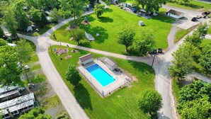 Vista aerea di una zona residenziale con piscina, un piccolo edificio e un'asta sventolante.