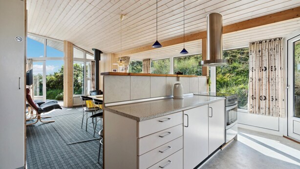 Una cocina moderna con una isla central, ventanas amplias y vistas al verdor.