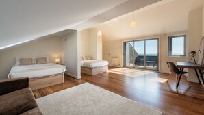 A spacious loft bedroom with a large bed, a second bed, a dining area, and a sliding glass door leading to a balcony. - Atlantic House - Beachfront Luxury House (Vila Nova de Gaia)