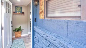 A hallway with a blue textured wall, a closed shutter door, a hanging plant, and a patterned rug. - Beautiful 3 bedroom 2 bathroom waterfront home on Drs. Lake (Orange Park)