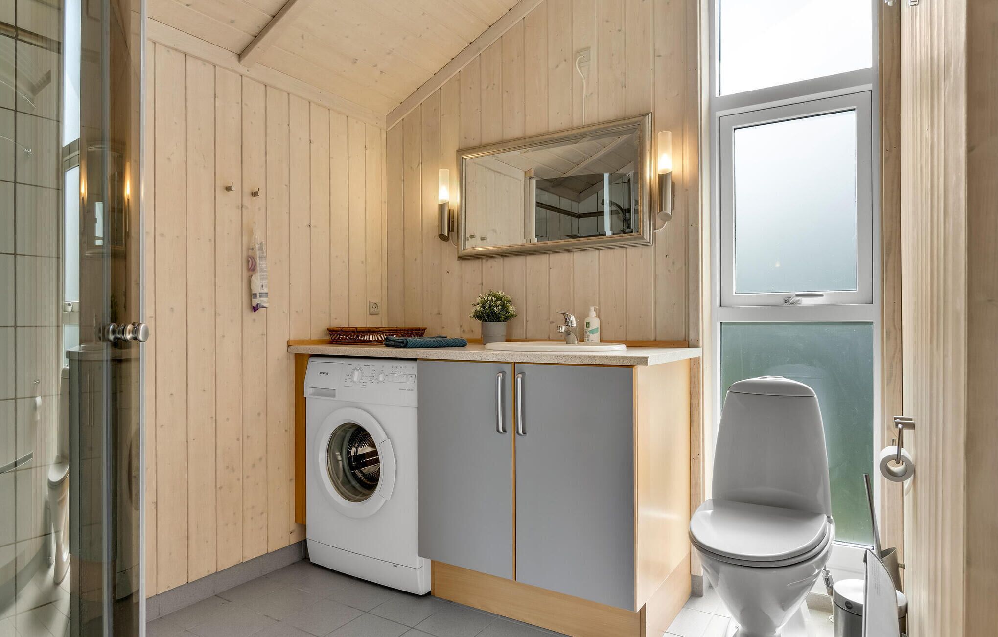 Ett modernt badrum med en inbyggd tvättmaskin, ett handfat och en toalett.