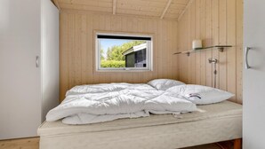 A bedroom with a bed, a window, and a wooden ceiling.