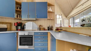 A modern kitchen with blue cabinets, a stainless steel oven, and a large window overlooking greenery.