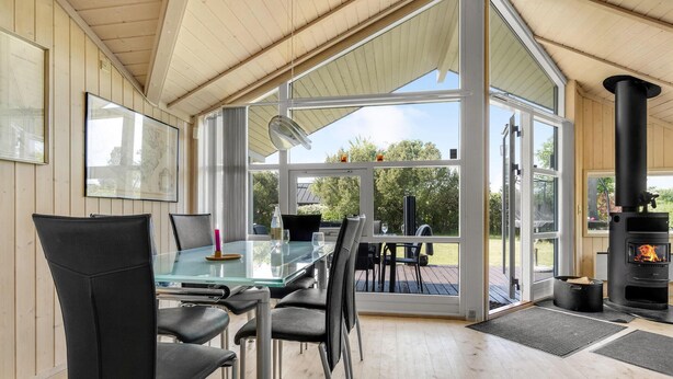 A modern interior with a glass dining table, black chairs, and a wood-burning stove.