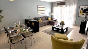 Ein modernes Wohnzimmer mit einem Glastisch, einer Couch und einem gelben Sessel.