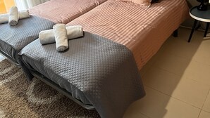 Ein Doppelbett mit einer gebügelten Kopfstütze, zwei Nachttische und ein großes Fenster mit Vorhängen.