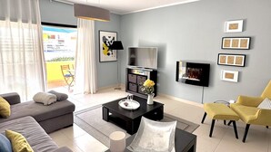 Ein modernes Wohnzimmer mit einer Couch, einem Couchtisch und einem an der Wand befestigten Fernseher.