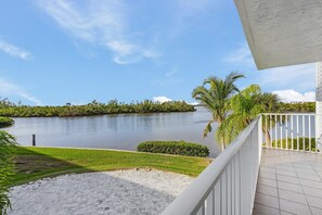 Une vue depuis un balcon donnant sur un lac, avec une zone pavée et une balustrade blanche.