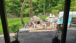 Eine Terrasse mit Gartenmöbeln, einem Feuerkorb und einem Pool.