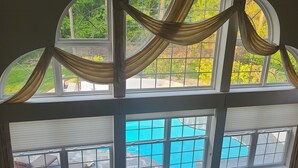 Ein Zimmer mit großem Fenster und Blick auf einen Swimmingpool.
