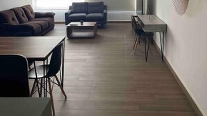 Een moderne woonkamer met een bank, salontafel en een eethoek.