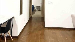 Ein geräumiges Zimmer mit Holzboden, einem Schreibtisch mit Stuhl und einem Bett im Hintergrund.