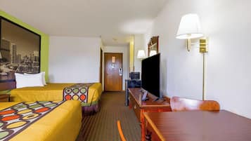Ein Hotelzimmer mit zwei Betten, einem Schreibtisch, einem Sessel, einem Fernseher und einer Lampe.