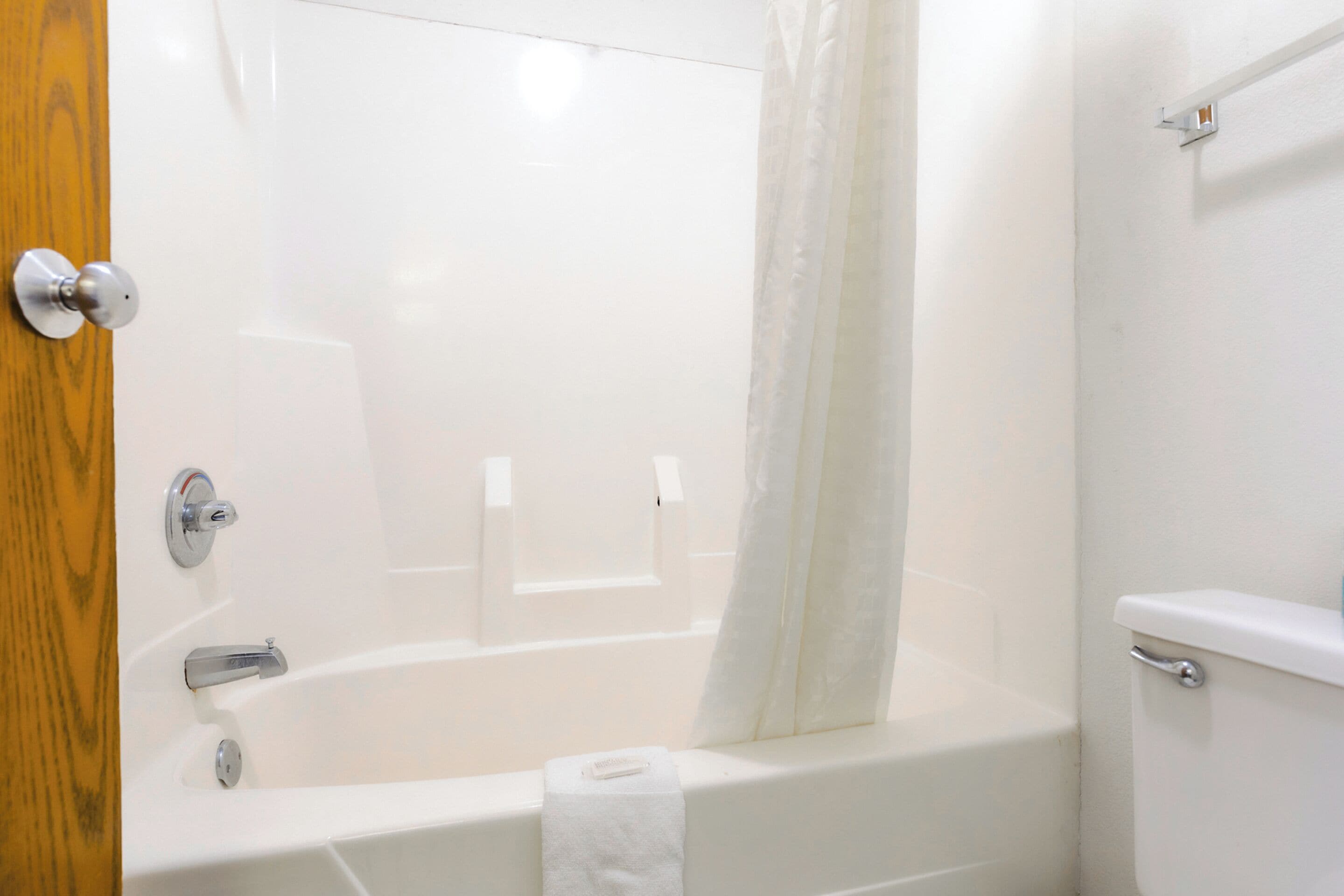 A bathroom with a bathtub, a toilet, and a shower curtain.