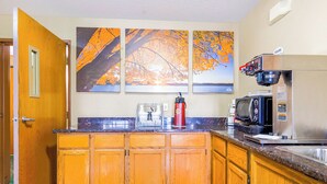 A kitchen with wooden cabinets, a microwave, a coffee machine, and a toaster.