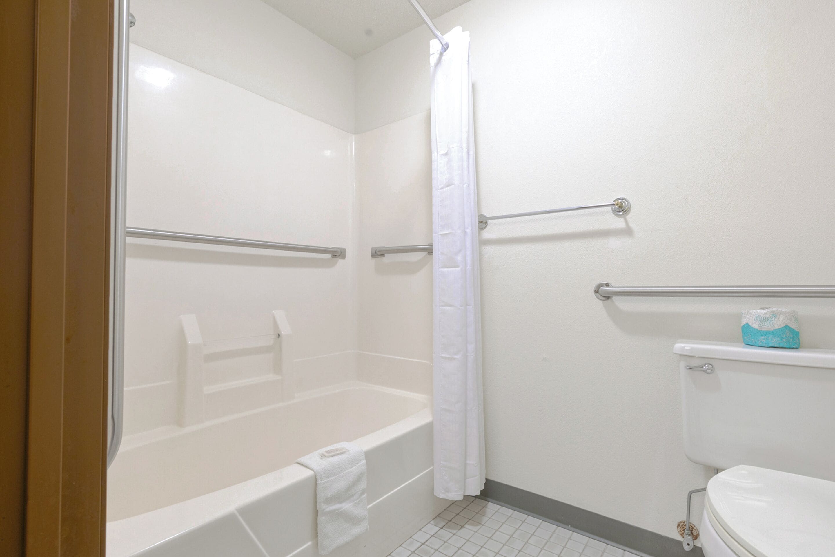 Ein Badezimmer mit Badewanne, Duschvorhang, Toilette und einer Haltestange.