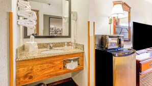 A bathroom with a sink, mirror, towel rack, hair dryer, and a microwave.