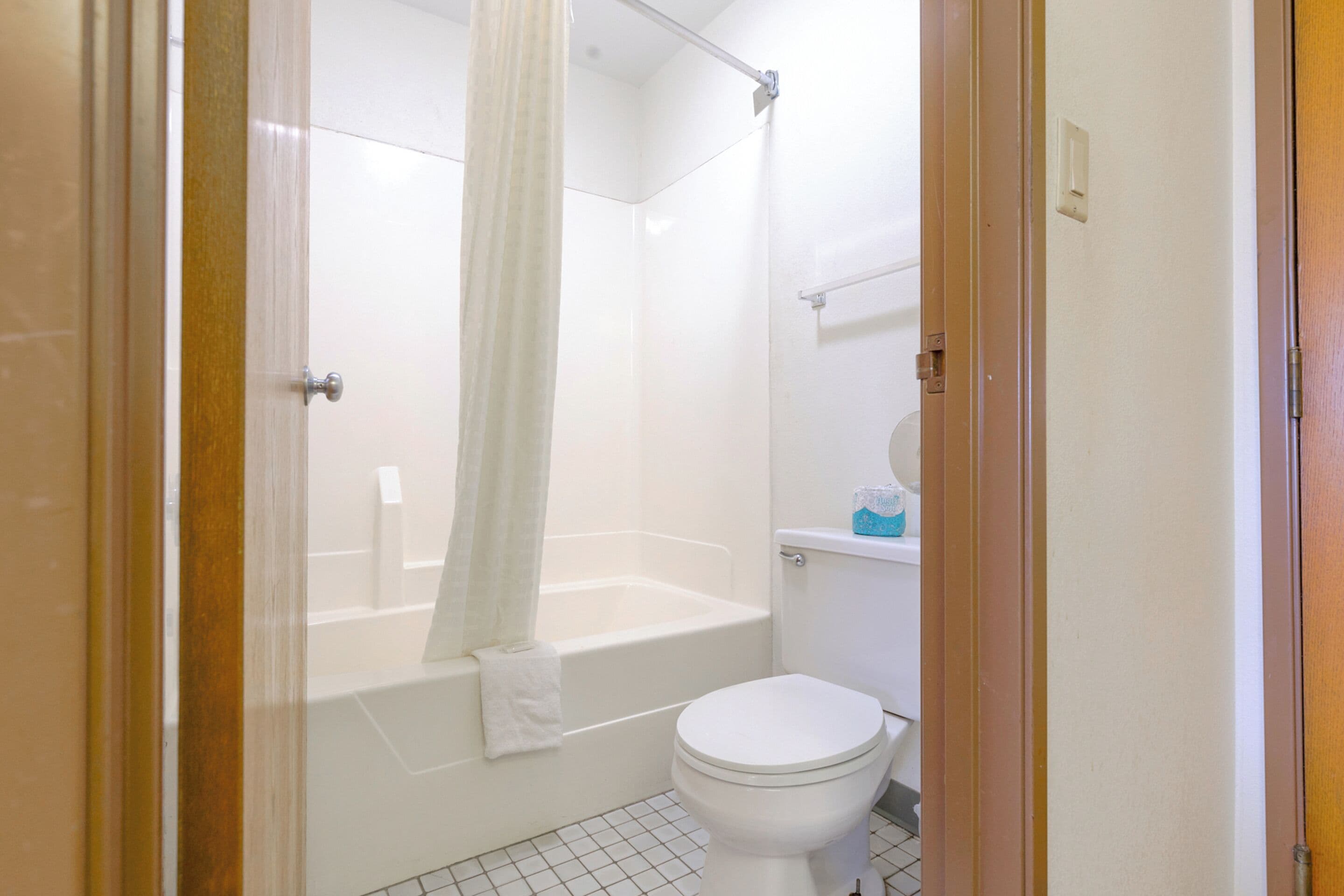 A bathroom with a bathtub, toilet, and a shower curtain.